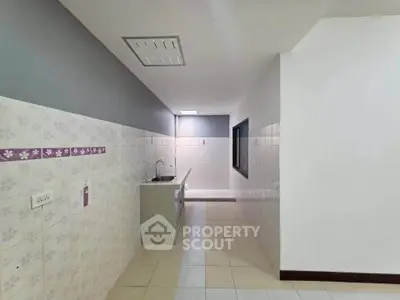Spacious kitchen with tiled walls and modern sink in a minimalist design.