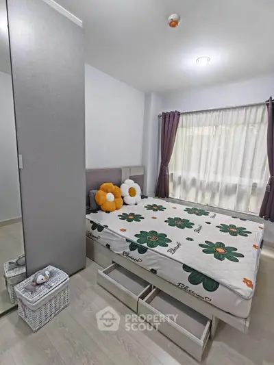 Cozy bedroom with floral bedding, mirrored wardrobe, and natural light from large window.