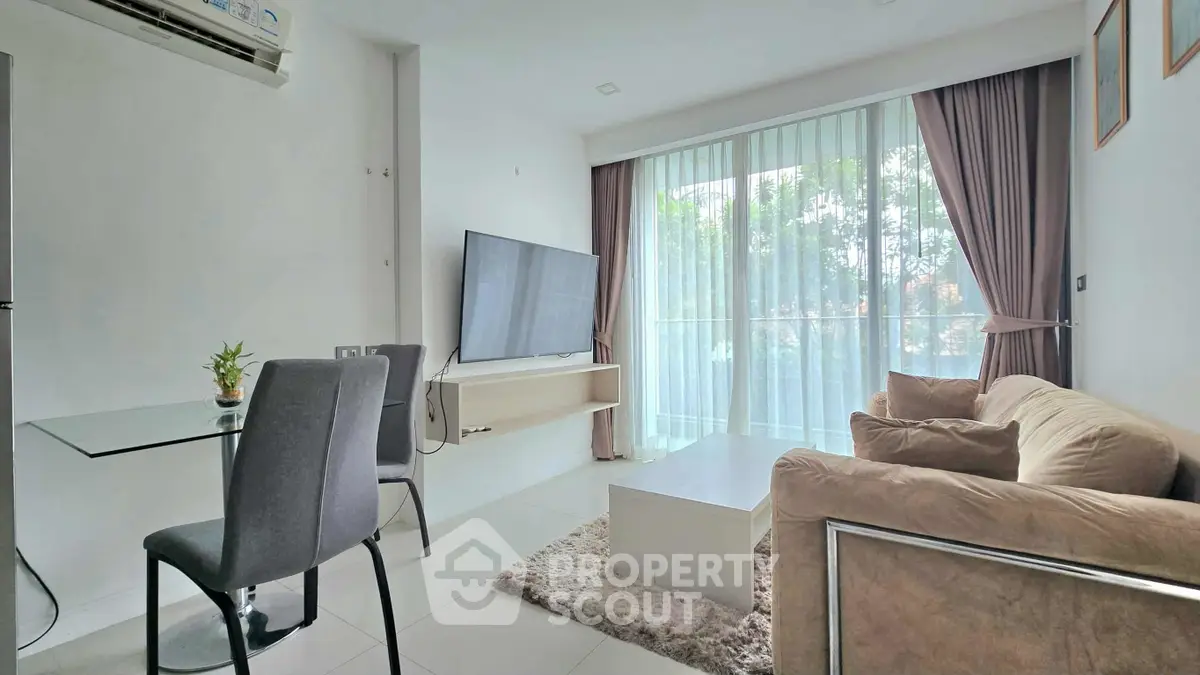 Modern living room with large TV, cozy sofa, and dining area near floor-to-ceiling windows.