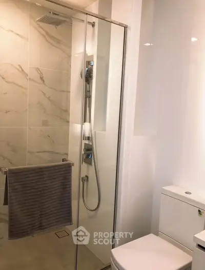 Modern bathroom with glass shower and sleek fixtures in luxury apartment.