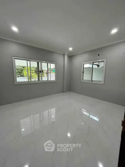 Spacious empty room with glossy marble flooring and large windows, perfect for customization.