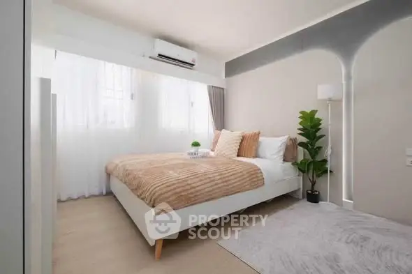Modern bedroom with stylish decor and natural light, featuring a cozy bed and elegant furnishings.