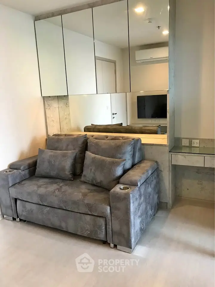 Modern living room with stylish gray sofa and mirrored wall accents