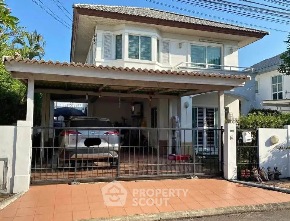 Charming two-story house with carport and gated entrance in a suburban neighborhood.
