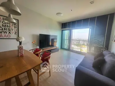 Modern living room with large TV and city view, featuring stylish decor and ample natural light.