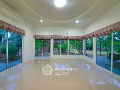 Spacious living room with large windows and garden view, perfect for natural light lovers.