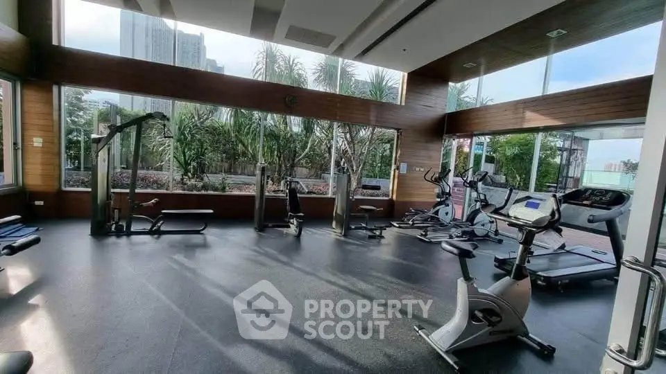 Spacious modern gym with large windows and city view, featuring various exercise equipment.