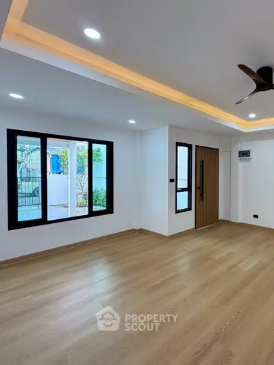 Spacious modern living room with wooden flooring and large windows for natural light.