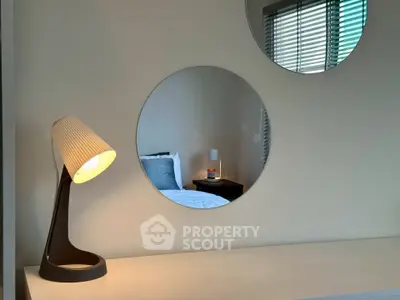 Modern bedroom with stylish lamp and round mirrors reflecting cozy decor.