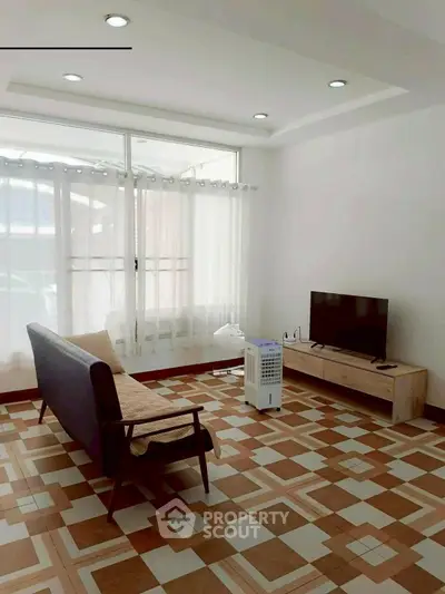 Bright living room with modern furniture and large windows, perfect for relaxation and entertainment.