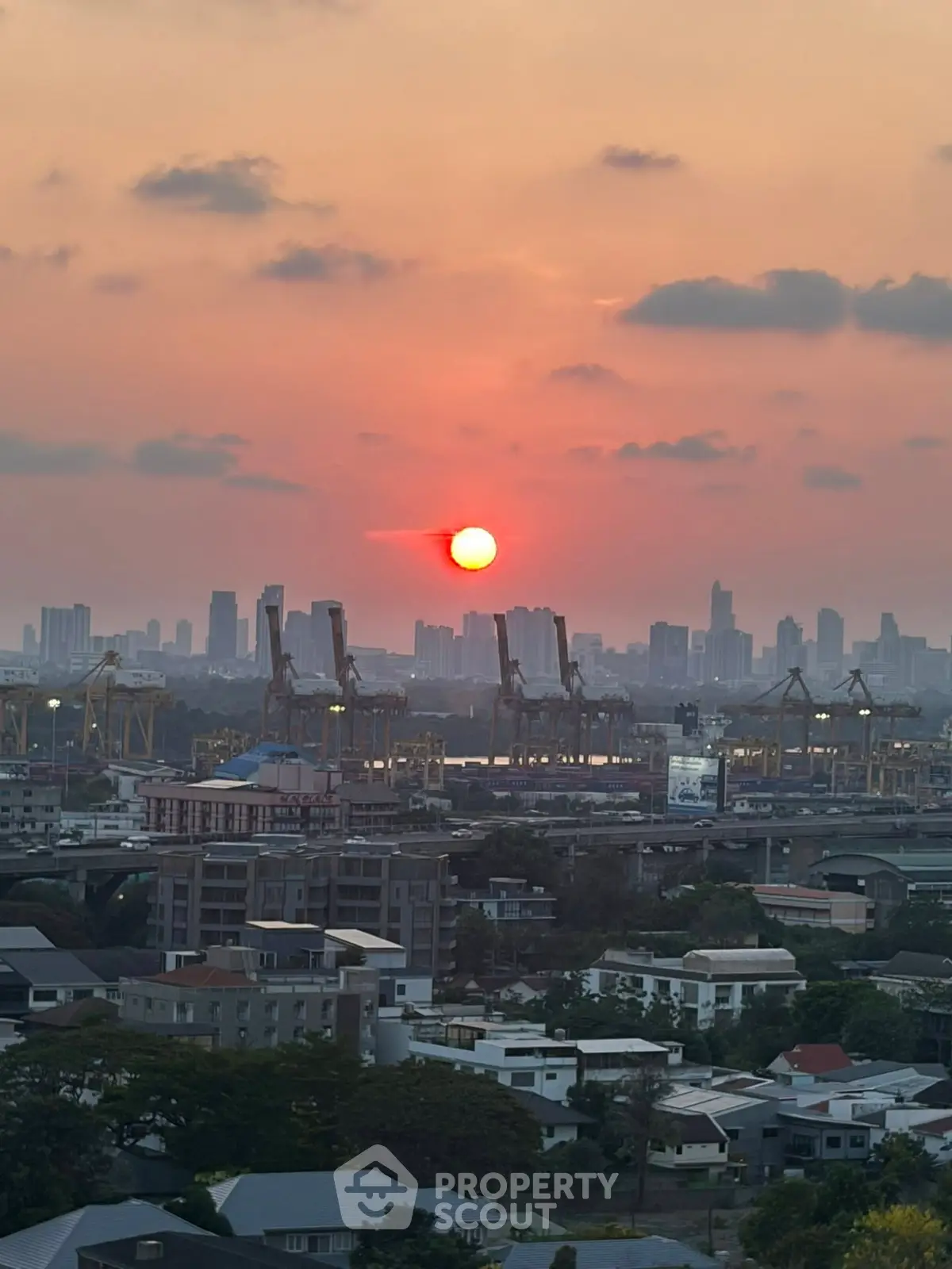 Stunning cityscape view at sunset with skyline and industrial cranes, perfect for urban living enthusiasts.
