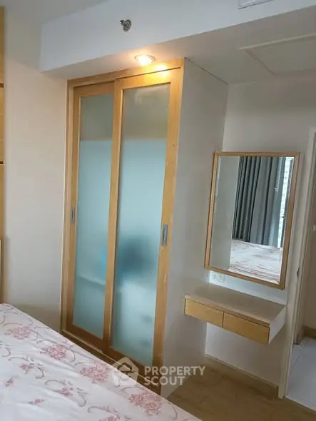 Cozy bedroom with built-in wardrobe and vanity mirror, perfect for modern living.