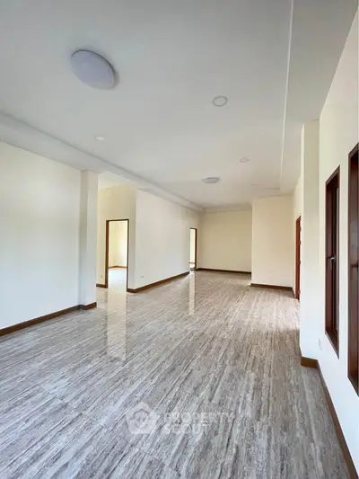Spacious empty room with elegant flooring and natural light