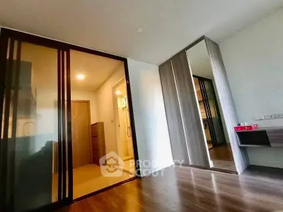 Modern bedroom with sliding glass doors and mirrored wardrobe in a stylish apartment.