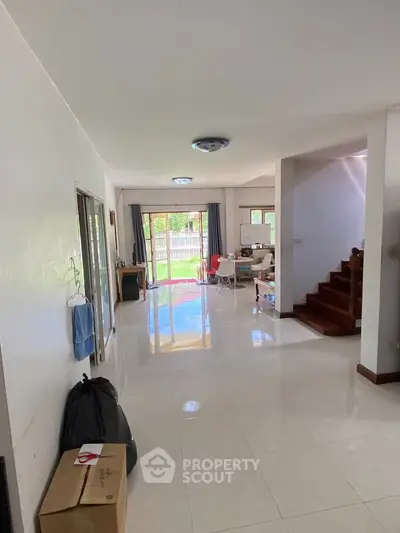 Spacious living room with glossy floors and garden view, ideal for family gatherings.