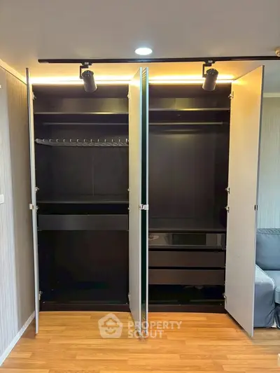 Spacious modern wardrobe with sleek black interior and ample storage space in a stylish apartment.