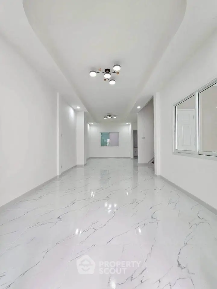 Spacious modern living room with elegant marble flooring and stylish ceiling lights.