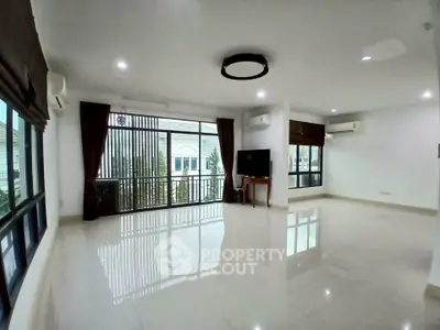 Spacious living room with large windows and modern lighting in a bright, airy home.