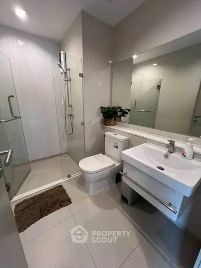 Modern bathroom with glass shower, sleek fixtures, and neutral tones.