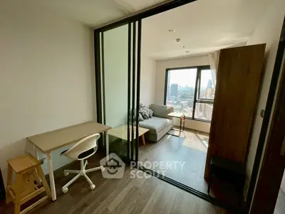 Modern apartment with sliding glass doors and city view, featuring a cozy living area and study space.
