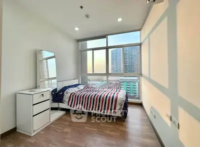 Modern bedroom with large windows offering stunning city views and stylish decor.