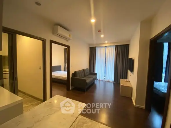 Modern apartment interior with open layout, featuring a cozy living room and adjacent bedroom.