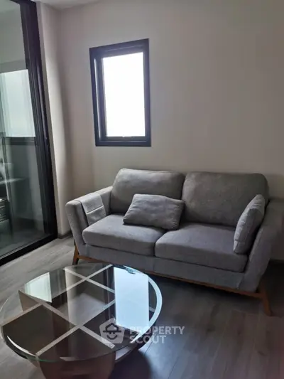 Modern living room with stylish gray sofa and glass coffee table