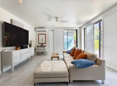 Luxurious modern living room with large TV, stylish sofa, and natural light from large windows.