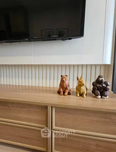 Modern living room with stylish wooden cabinet and decorative animal figures under a mounted TV.