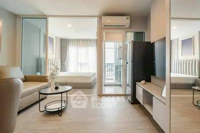 Modern open-plan living room with sleek furniture and natural light, featuring a cozy bedroom view.