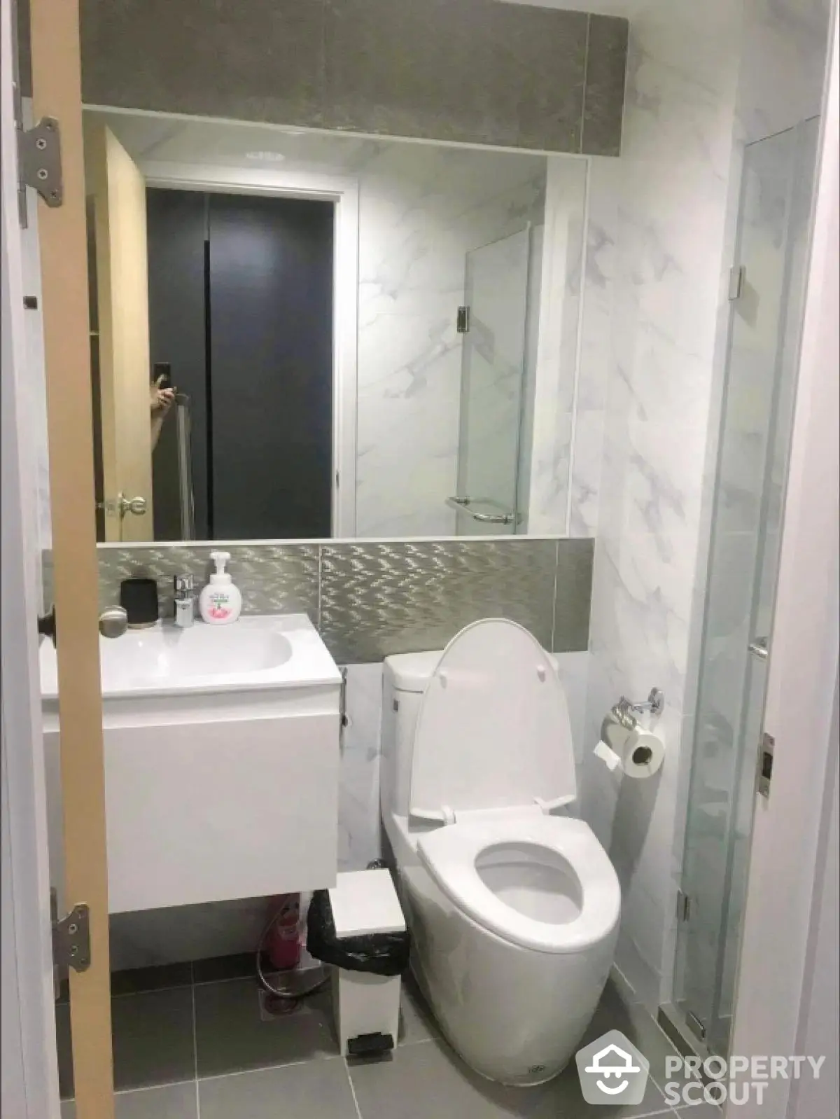 Modern bathroom with sleek design, featuring a toilet, sink, and glass shower enclosure.