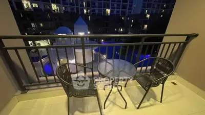 Charming balcony view overlooking illuminated pool in modern apartment complex at night.