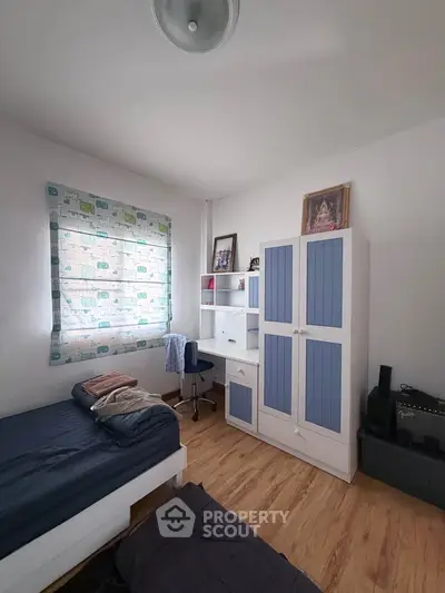 Cozy bedroom with wooden flooring and stylish blue furniture, perfect for a comfortable living space.