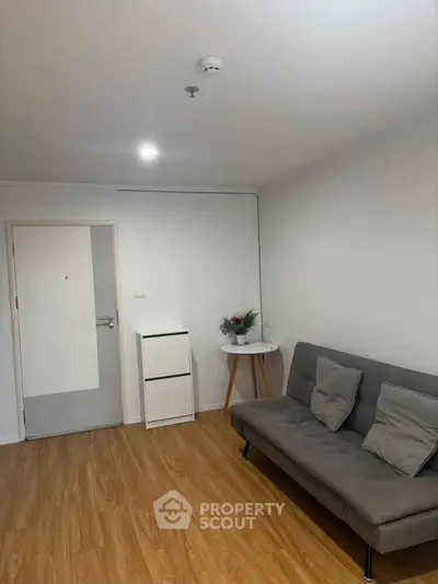 Modern living room with wooden flooring and stylish gray sofa, perfect for cozy relaxation.