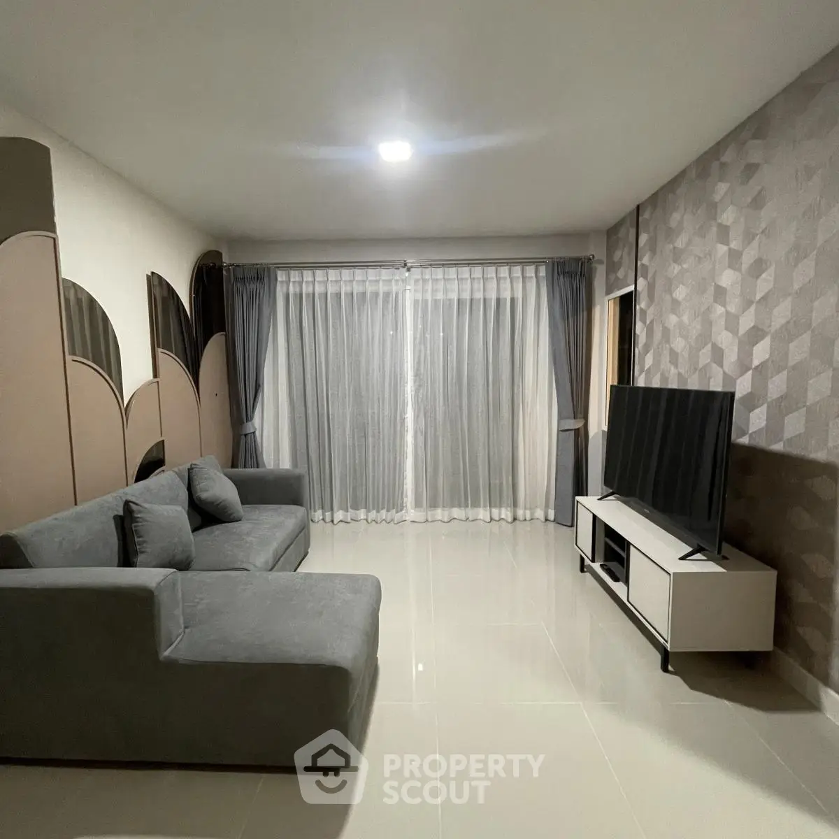 Modern living room with sleek grey sofa and large TV, perfect for relaxation.