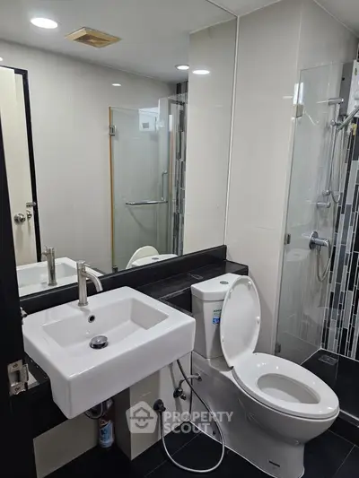 Modern bathroom with sleek fixtures and glass shower enclosure in a contemporary apartment.