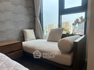 Cozy bedroom nook with city view, featuring elegant chaise lounge and modern decor.