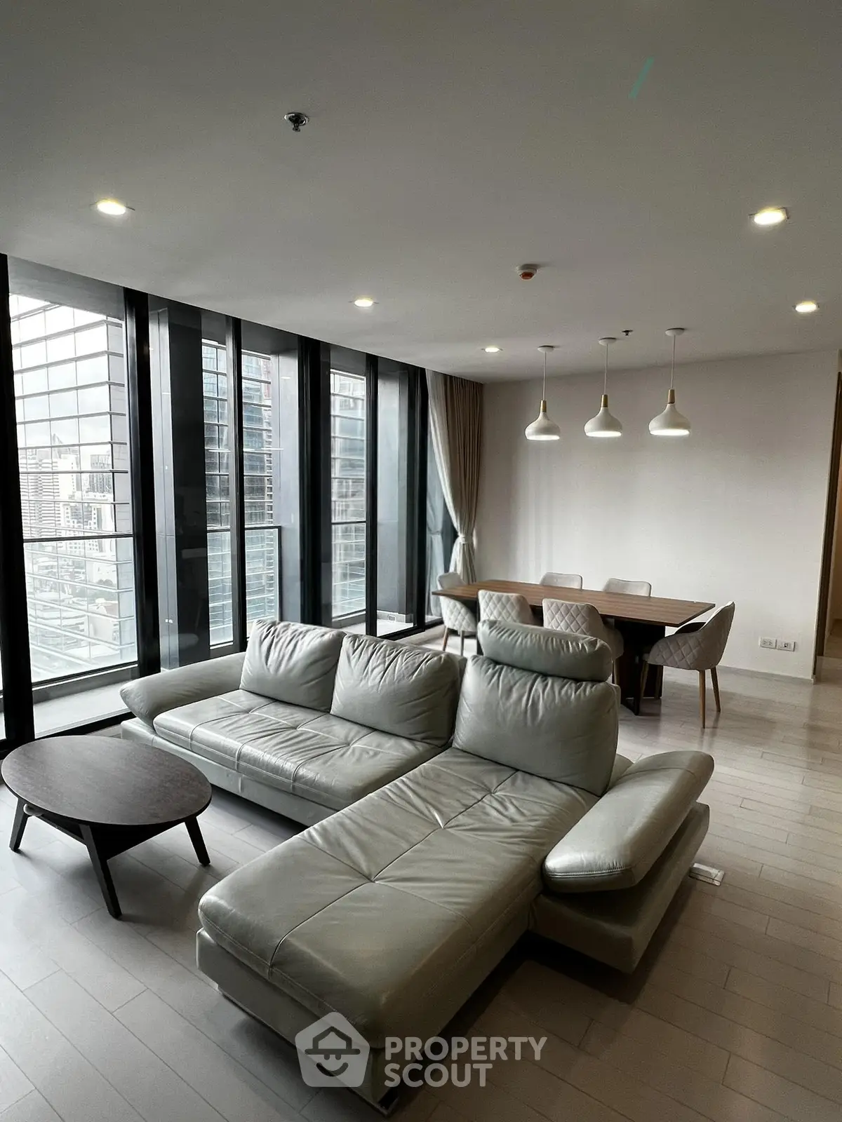 Modern living room with sleek furniture and city view through large windows.