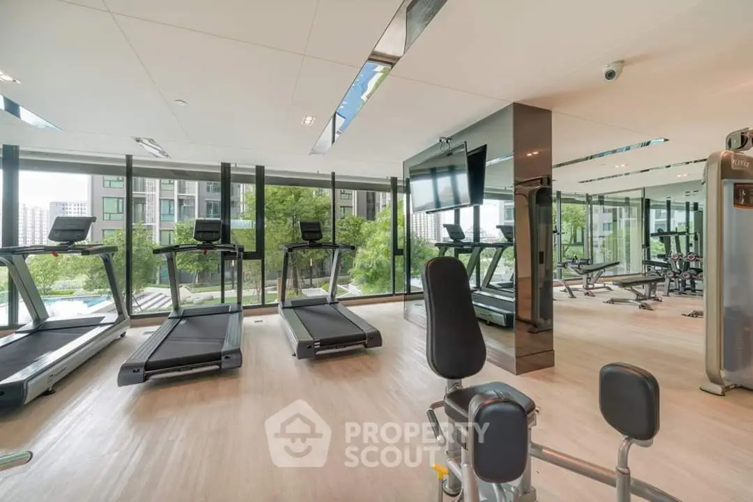 Modern gym with large windows and fitness equipment in luxury apartment building.