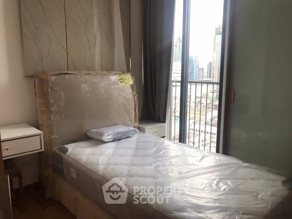 Modern bedroom with single bed and city view balcony in high-rise apartment.