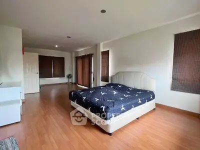 Spacious bedroom with wooden flooring and stylish bed in modern home