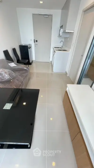 Modern apartment interior with sleek kitchen and cozy living area, featuring glossy tiled floors and contemporary furniture.
