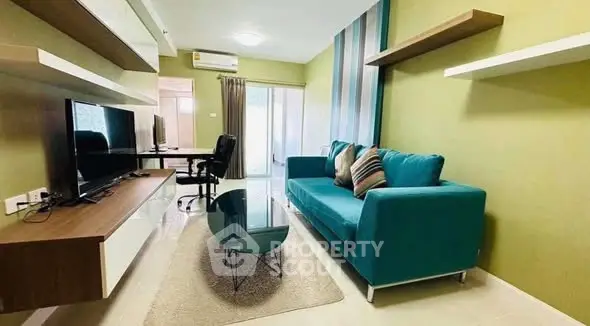 Modern living room with teal sofa, wall-mounted TV, and stylish decor in a cozy apartment.