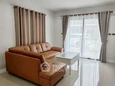 Modern living room with brown leather sofa and large windows for natural light.