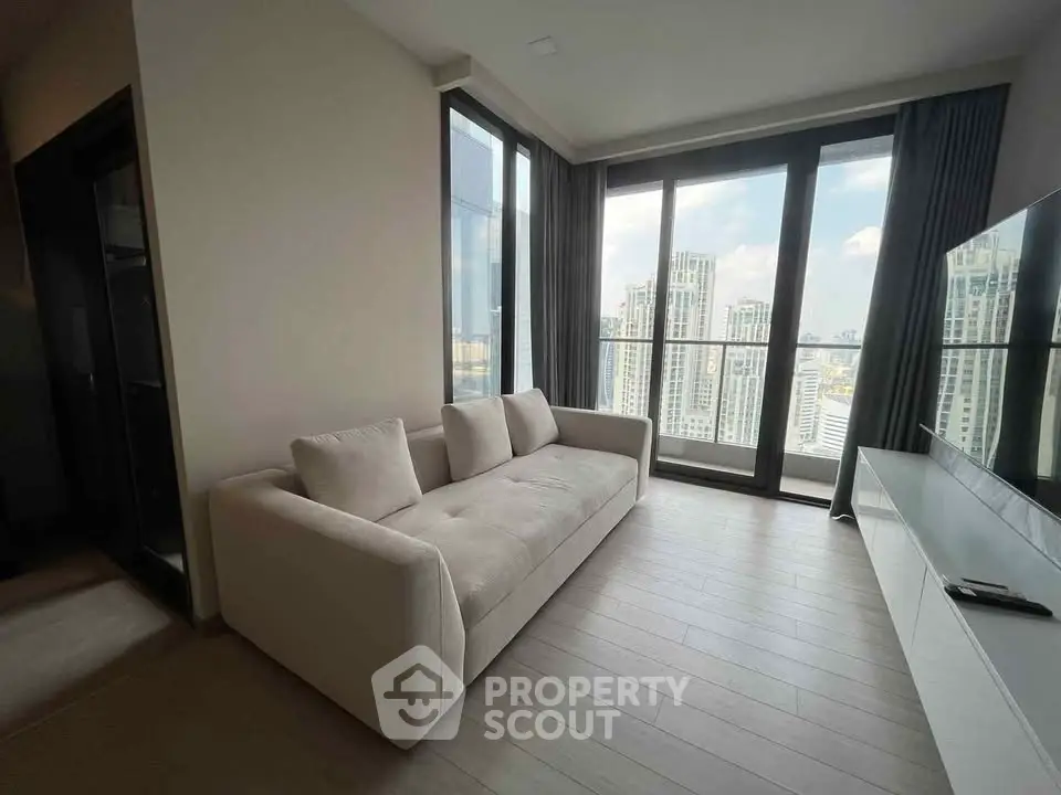 Modern living room with large windows offering stunning city views in a high-rise apartment.