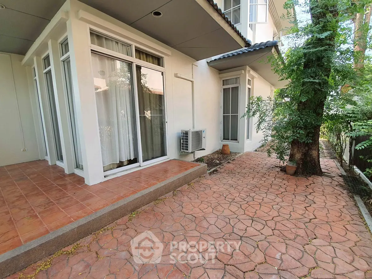 Charming exterior view of a modern home with spacious patio and lush greenery, perfect for outdoor relaxation.