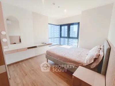 Bright and modern bedroom with large windows and stylish furnishings in a high-rise apartment.