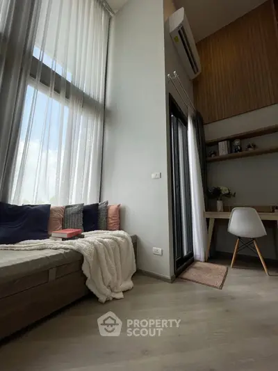 Modern living room with high ceilings and cozy seating area, featuring a study nook and large windows.