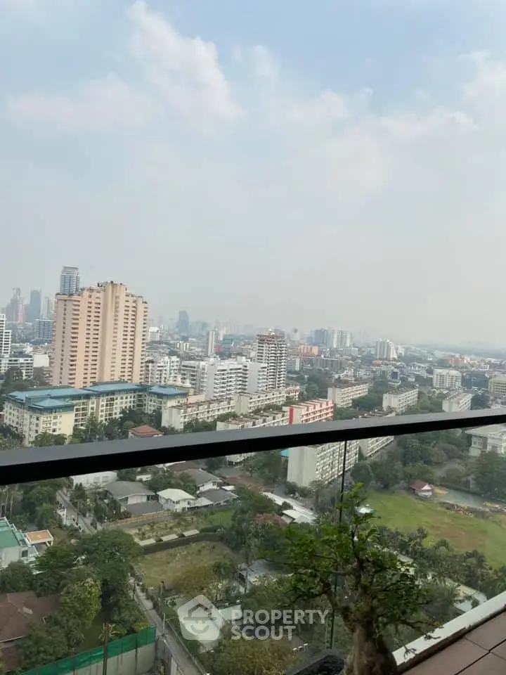 Stunning cityscape view from a high-rise balcony, showcasing urban skyline and lush greenery.