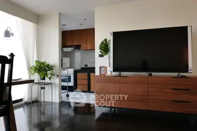 Modern living room with sleek TV stand and open kitchen layout, featuring stylish wooden cabinetry and contemporary decor.
